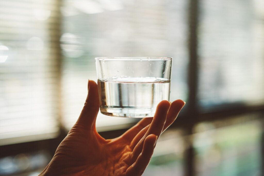 person holding clear glass cup water and keto